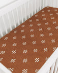 Brown crib sheet with white floral pattern on a white crib