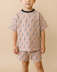 Child wearing a pink outfit with lightning bolt patterns on a beige background