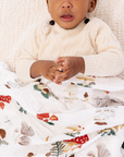 Child wrapped in a colorful blanket with a white knit blanket underneath