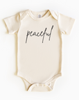 Baby wearing “Peaceful” affirmation bodysuit – Christian script design organic cotton outfit by Lumiere Vive