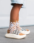 Person wearing checkered socks with a peace symbol design on a neutral background