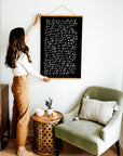 Woman displaying black The Lord Is My Shepherd wall art beside a green accent chair.