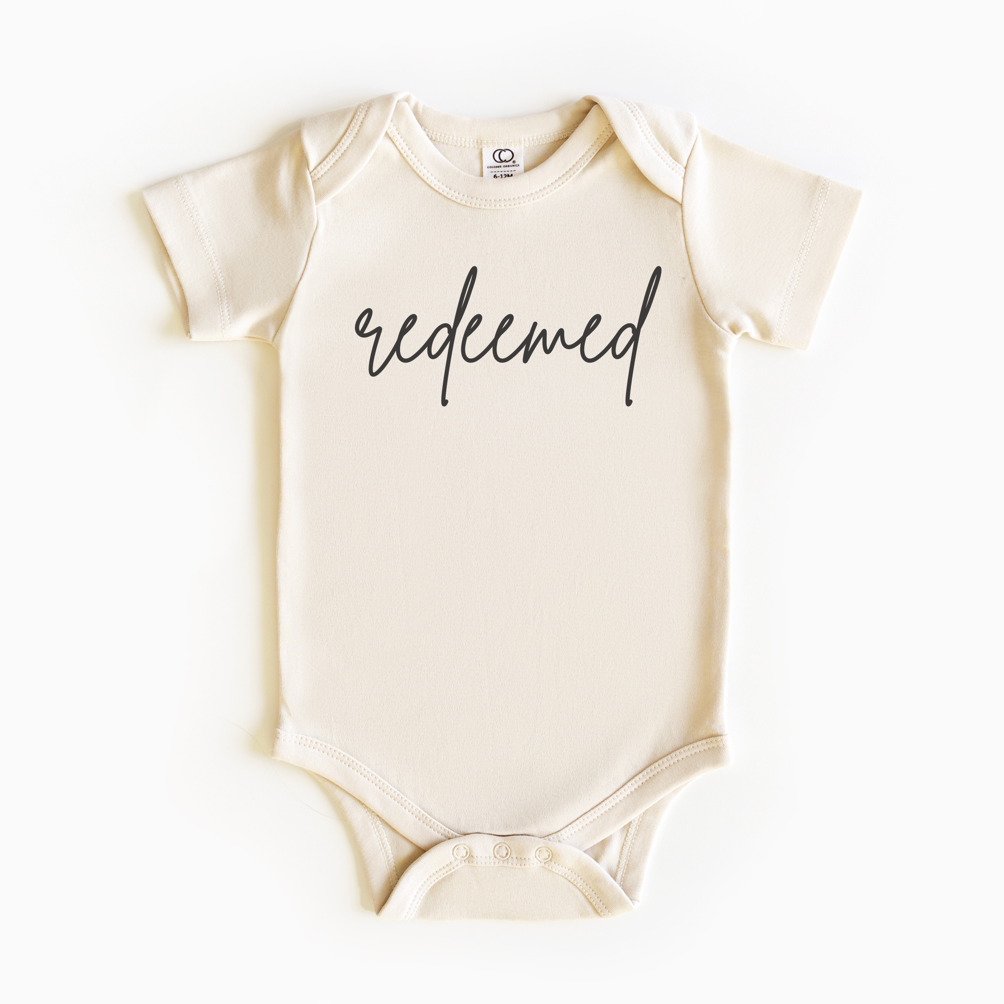 Baby wearing “Redeemed” affirmation bodysuit – Christian script design organic cotton outfit by Lumiere Vive