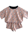 Two-piece outfit with a top and shorts featuring lightning bolt patterns on a beige background.