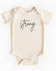 Baby wearing “Strong” affirmation bodysuit – Christian script design organic cotton outfit by Lumiere Vive