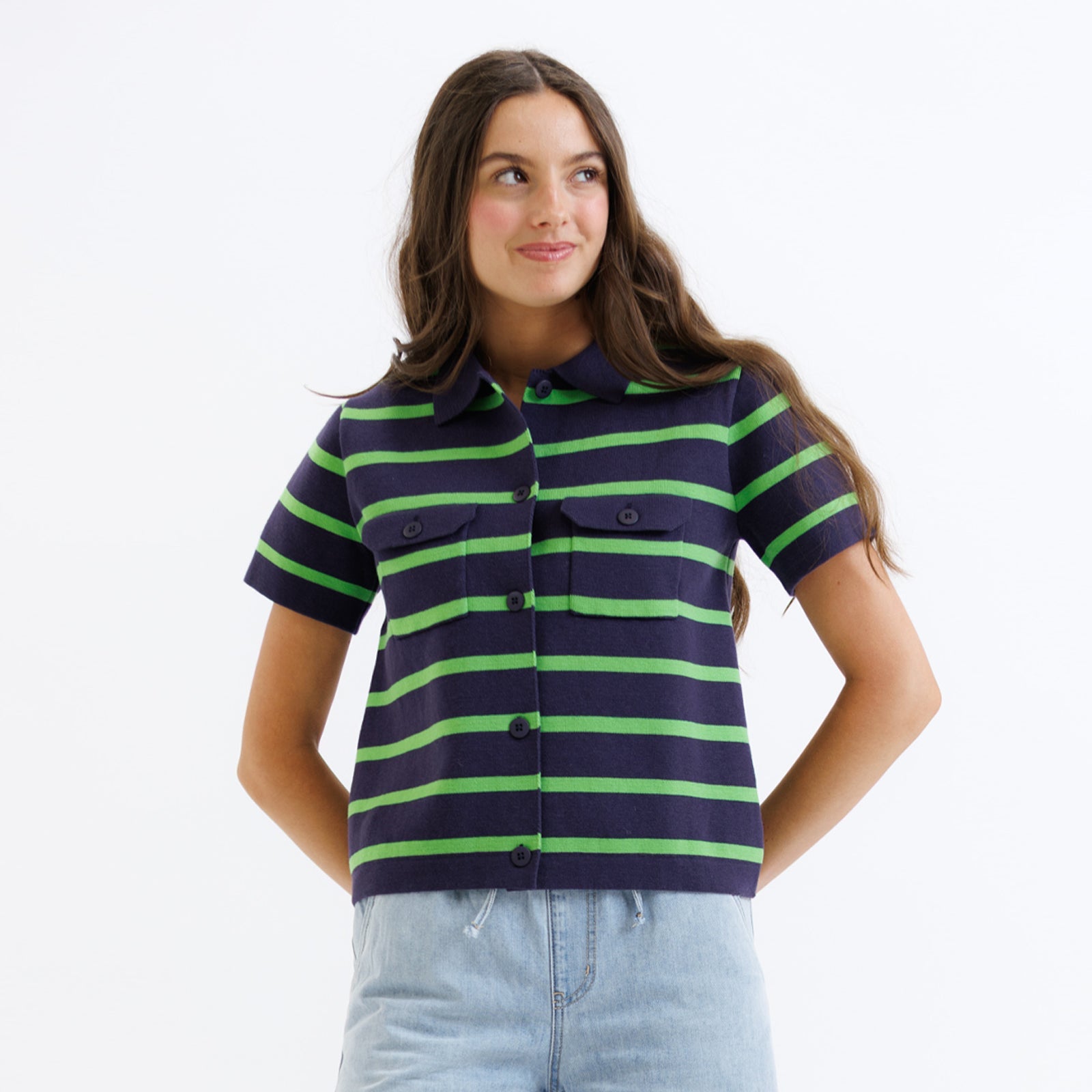 Woman wearing a navy and green striped shirt with light blue jeans on a white background