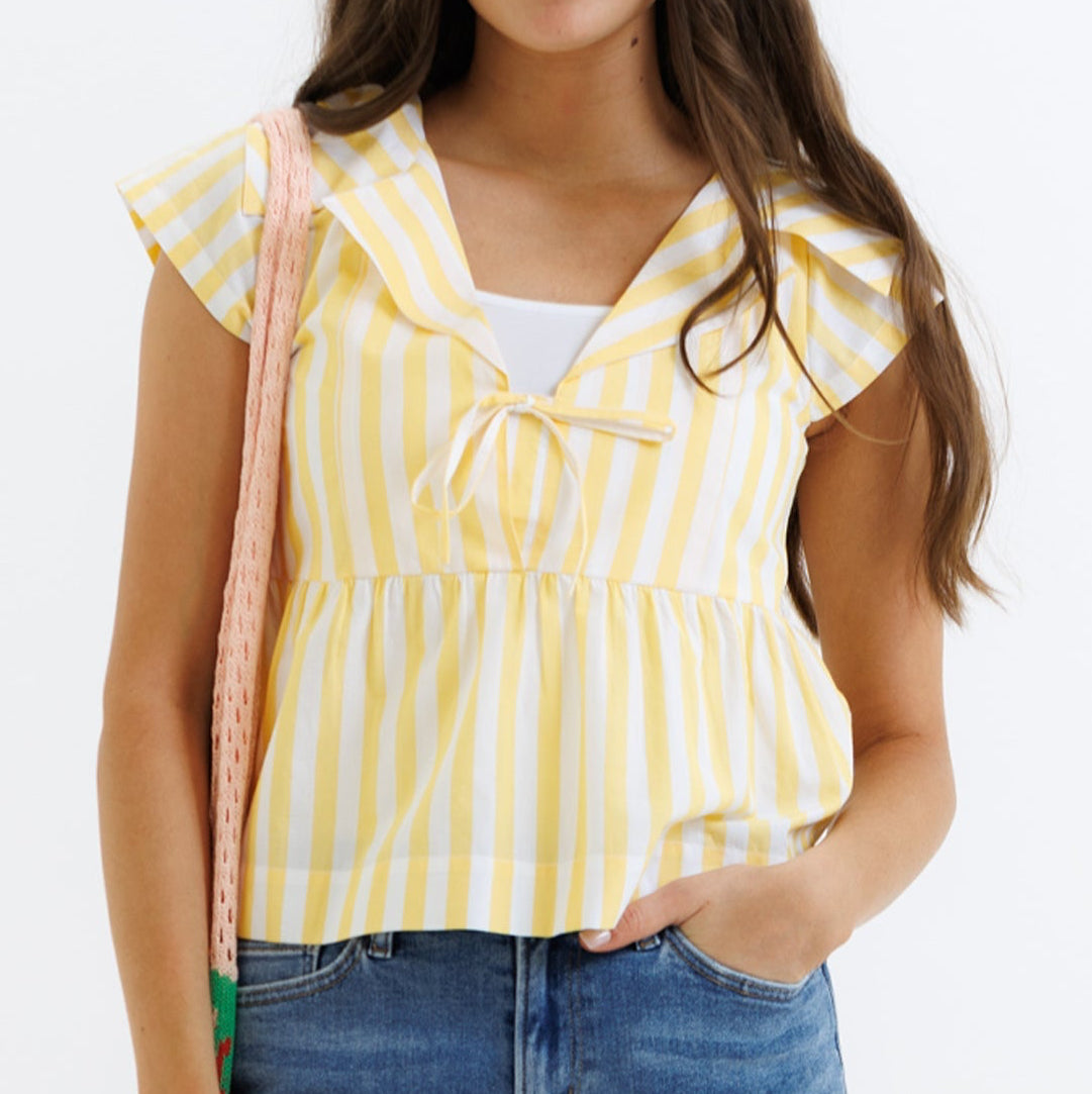 Woman wearing a yellow striped top and blue jeans on a white background
