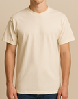 Male model wearing a neutral American Apparel 1301 Heavyweight Cotton T-Shirt, photographed in a warm beige studio — unisex blank ideal for custom printing by Lumiere Vive.