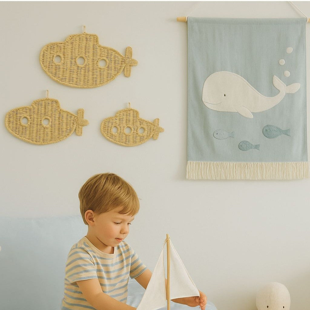 Child playing with a wooden boat in a room with whale decorations and Lullaby Rattan branding.
