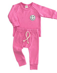 Pink baby outfit with smiley face design on a white background