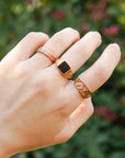 Hand wearing three rings with a blurred green background