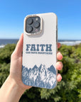 Faith Can Move Mountains iPhone case held outdoors with greenery and blue sky in the background