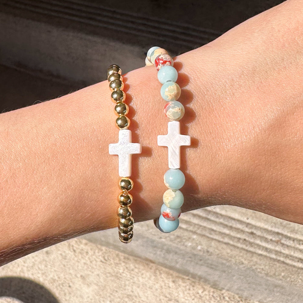 Three bracelets on a wrist with a neutral background