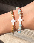 Three bracelets on a wrist with a neutral background