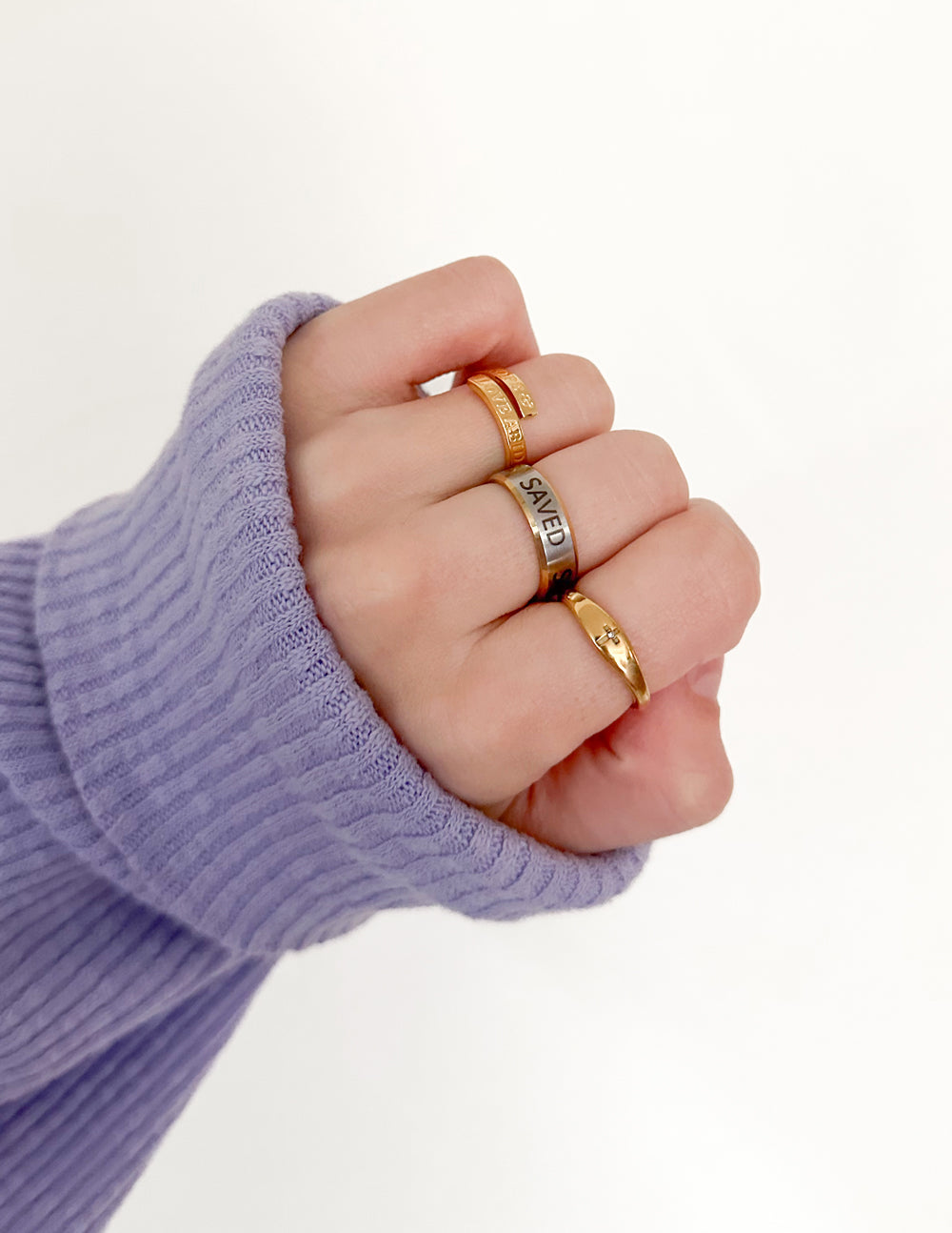 Cross Gemstone Gold-Tone Ring styled with other rings on a hand extending from a lavender sweater sleeve