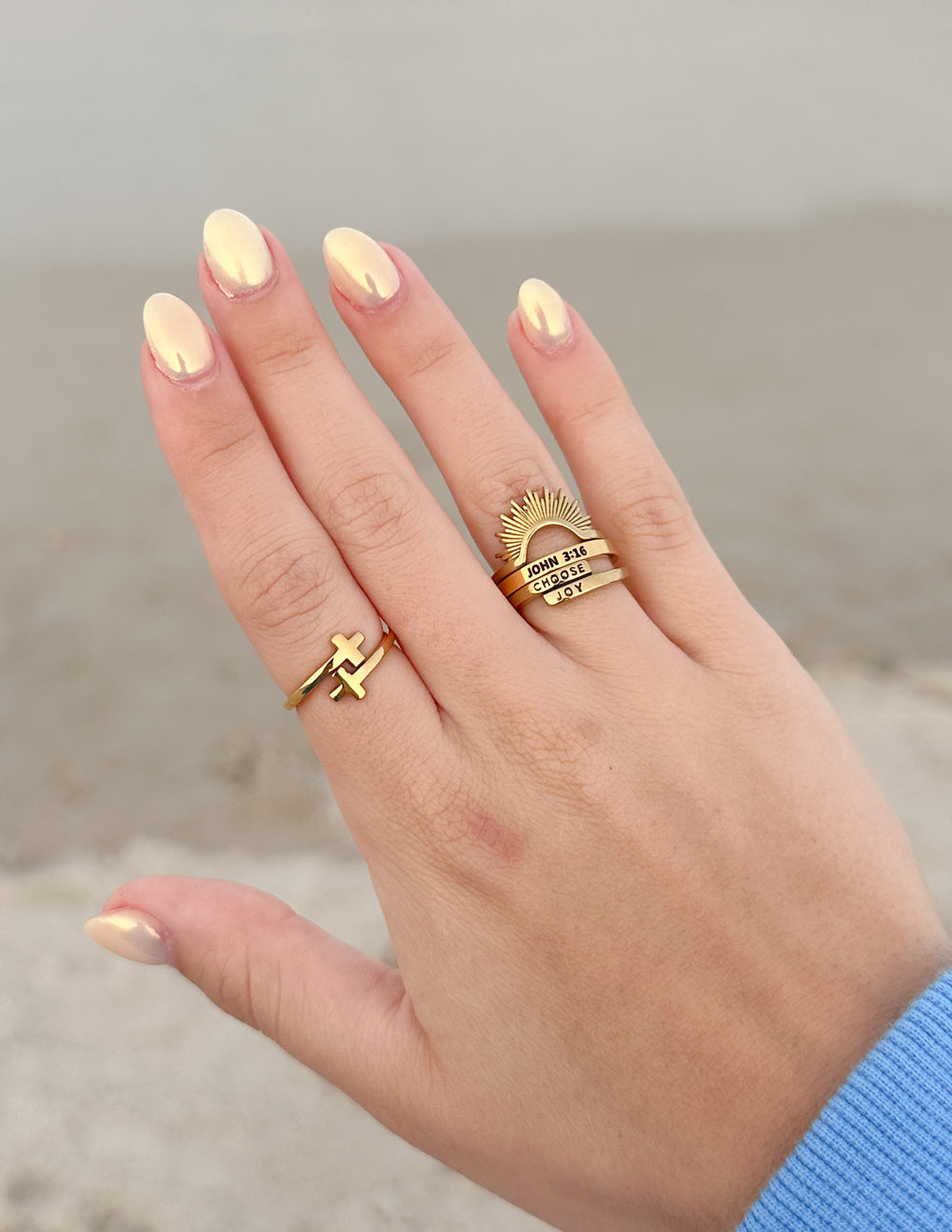 Gold-tone Wrapped Double Cross Ring worn alongside other rings with a blue sleeve