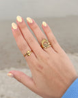 Gold-tone Wrapped Double Cross Ring worn alongside other rings with a blue sleeve