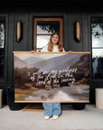 Person holding a large Goodness of God canvas wall banner with a mountain landscape, Psalm 27:13 lettering, and wood banner frames