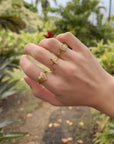 Textured Wrapped Cross Gold-Tone Ring styled with other rings on a hand outdoors