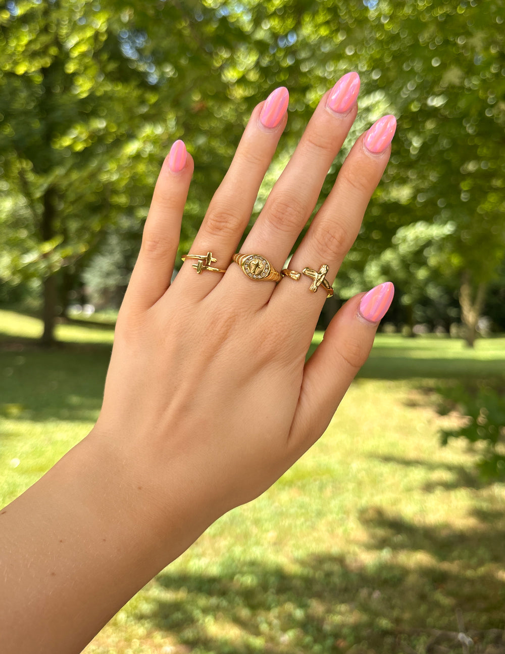 Textured Wrapped Cross Gold-Tone Ring styled with several rings on a hand outdoors