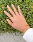 Open Cross Gold-Tone Ring styled with other gold-tone jewelry against green foliage