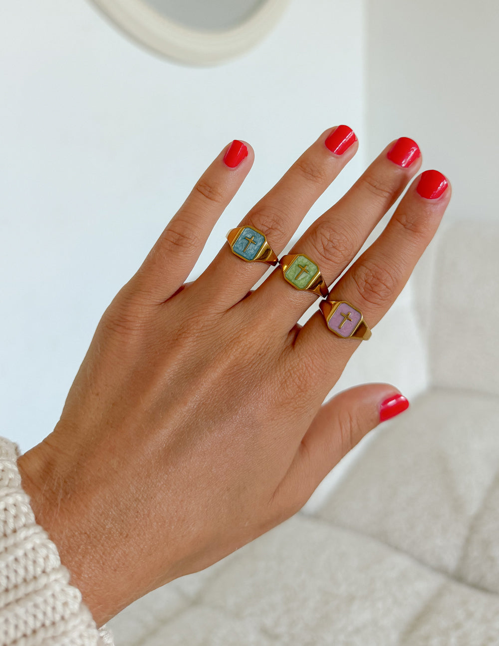 Lilac Enamel Cross Ring styled with other enamel cross rings and a cream knit sleeve indoors