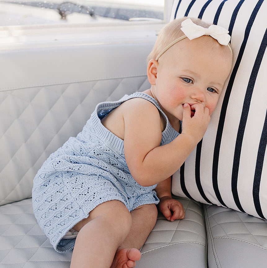Baby sitting on a white couch with a striped pillow