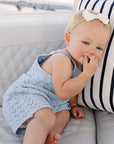 Baby sitting on a white couch with a striped pillow