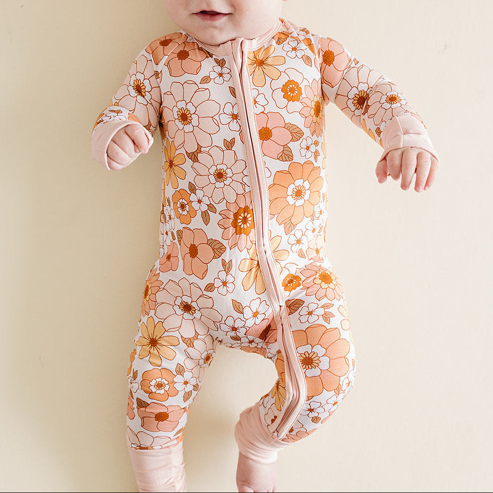 Baby wearing a floral onesie on a plain background