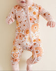 Baby wearing a floral onesie on a plain background
