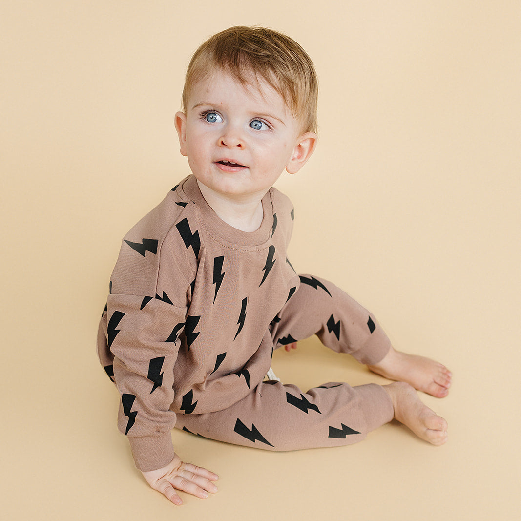 Child wearing a brown outfit with black patterns on a beige background