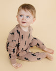 Child wearing a brown outfit with black patterns on a beige background