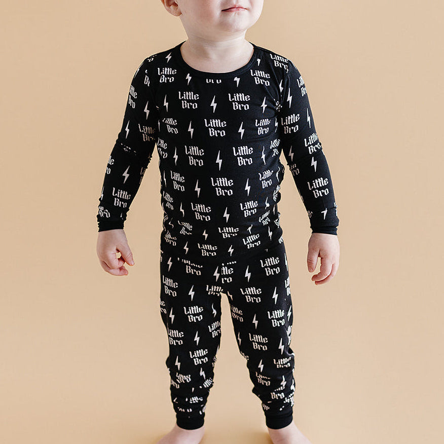 Baby wearing a black onesie with white text and graphics on a beige background