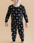 Baby wearing a black onesie with white text and graphics on a beige background