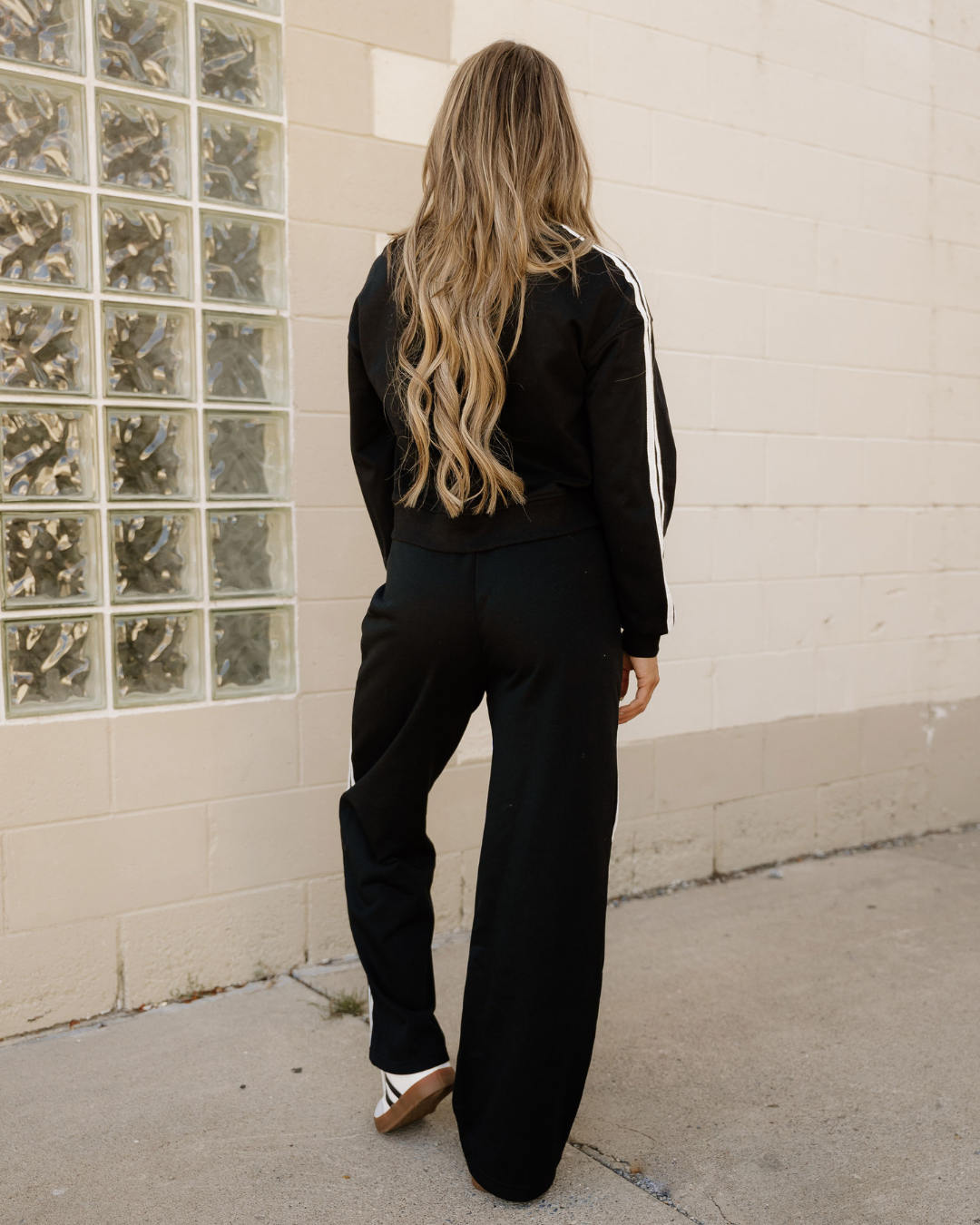Back view of black varsity stripe crewneck and sweatpants set