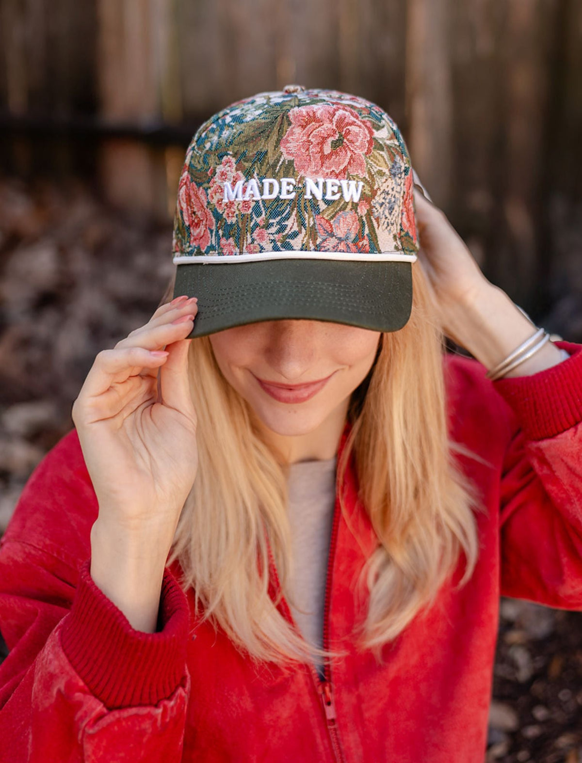Model wearing the Made New floral hat with white embroidered lettering and a dark curved brim