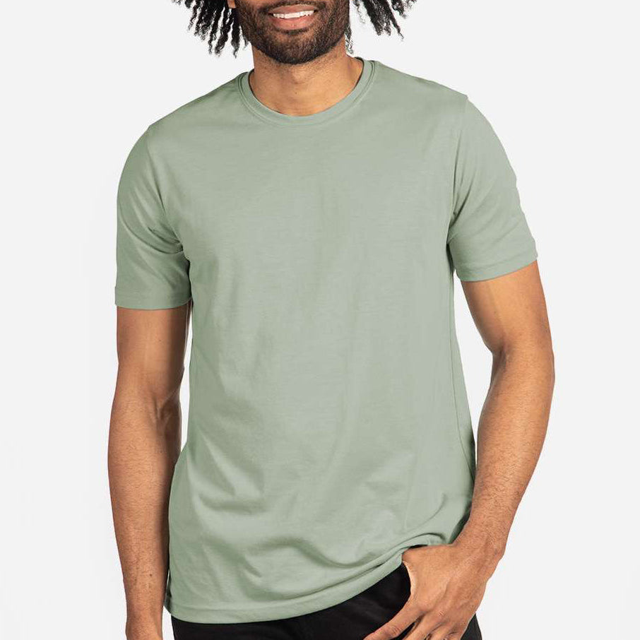 Male model wearing a sage green Next Level 3600 Unisex Cotton T-Shirt on a light background — premium ringspun cotton blank ideal for custom printing by Lumiere Vive.