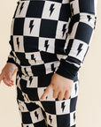 Black and white checkered outfit with lightning bolt pattern on a beige background