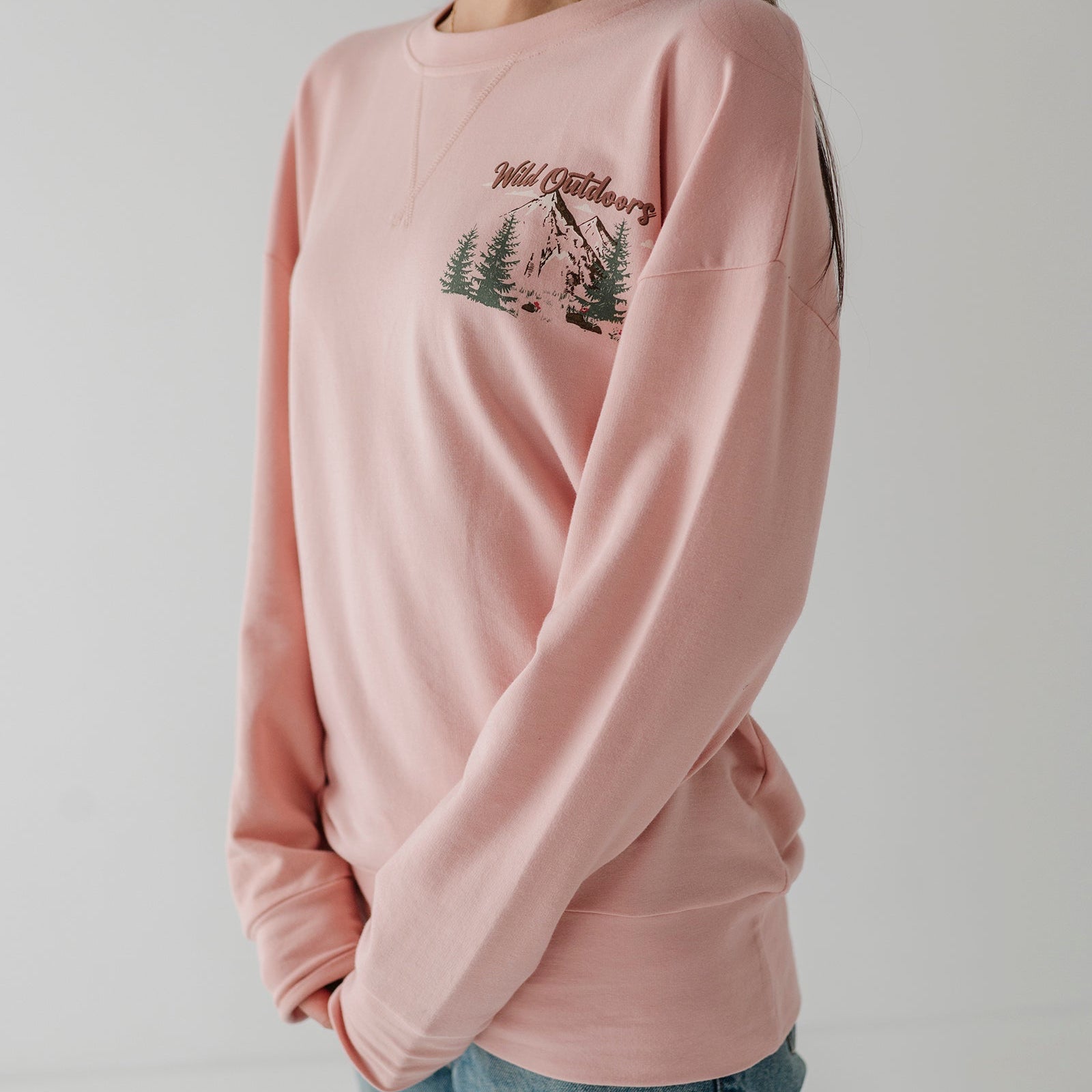Person wearing a pink sweatshirt with a graphic design on a plain background