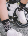 Person wearing white sneakers and patterned socks on a bicycle.