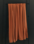 Brown curtain hanging on a black metal ladder against a dark wall