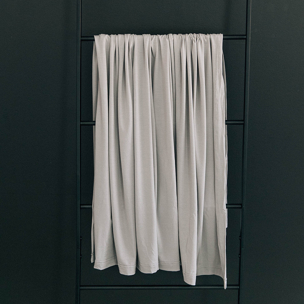 White curtain hanging on a black ladder against a dark wall
