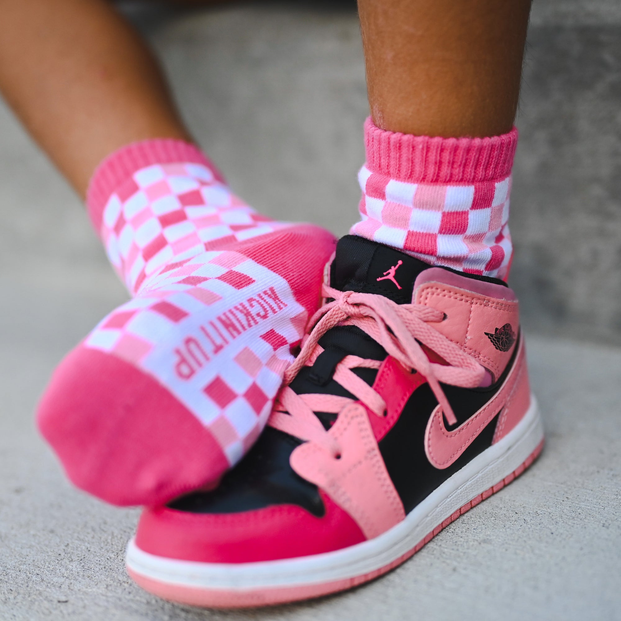 Pink and black sneakers with checkered socks on a neutral background