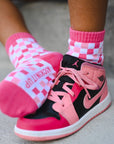Pink and black sneakers with checkered socks on a neutral background