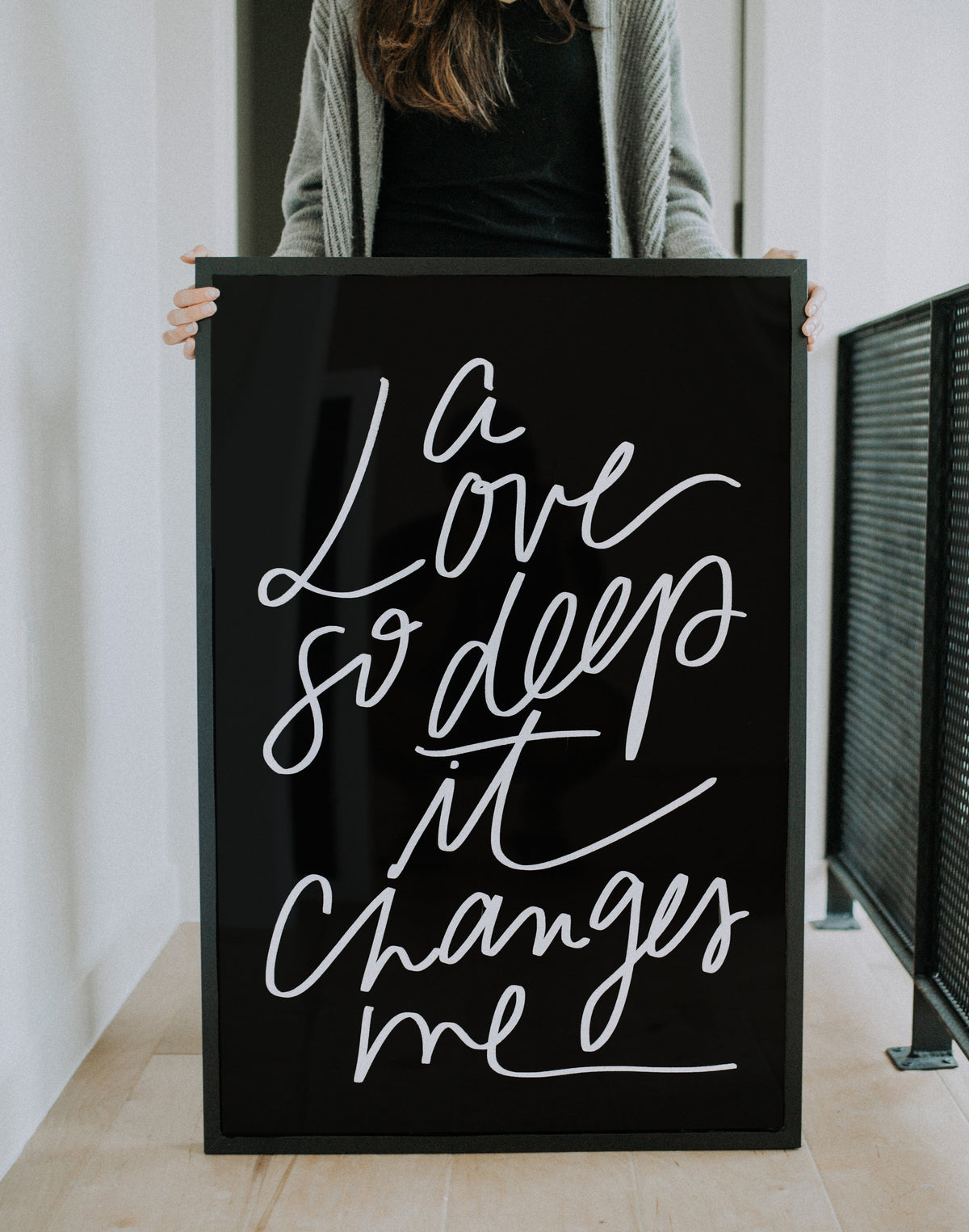 Large A Love So Deep It Changes Me artwork held upright, showing white script on a black background
