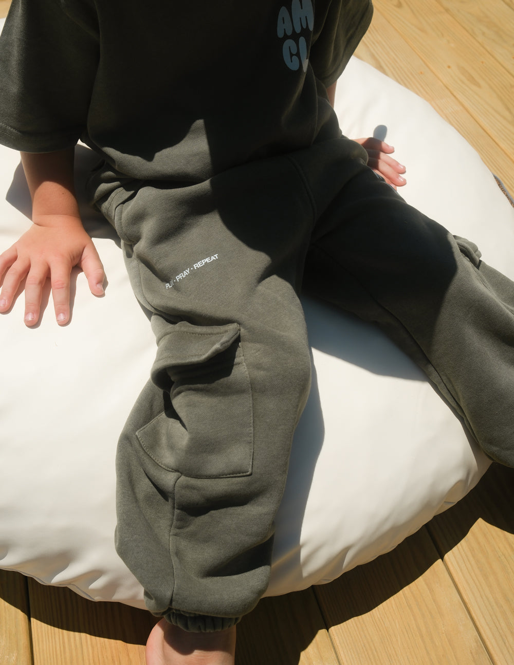 Child wearing hunter green Amen Club cargo sweatpants with side cargo pockets