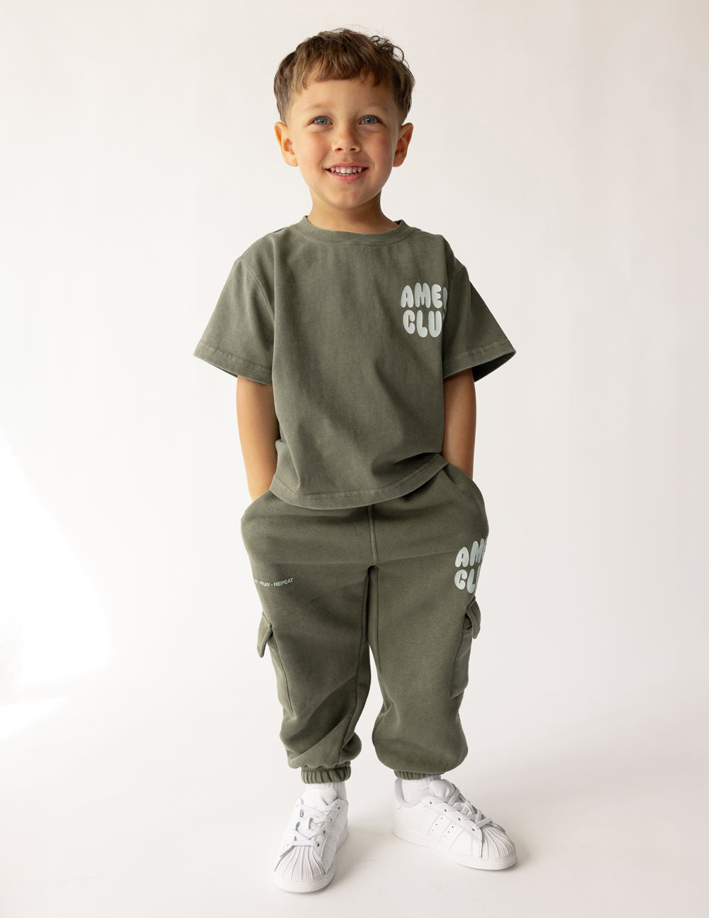 Child modeling hunter green Amen Club cargo sweatpants with a coordinating shirt