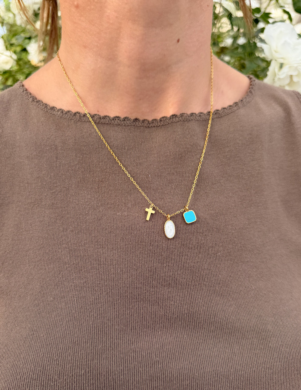 Ascend Charm Link Necklace worn with a brown top outdoors, showing three delicate pendants
