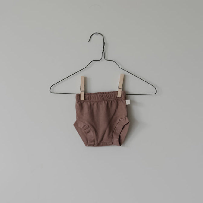 Brown baby romper on a hanger against a plain background