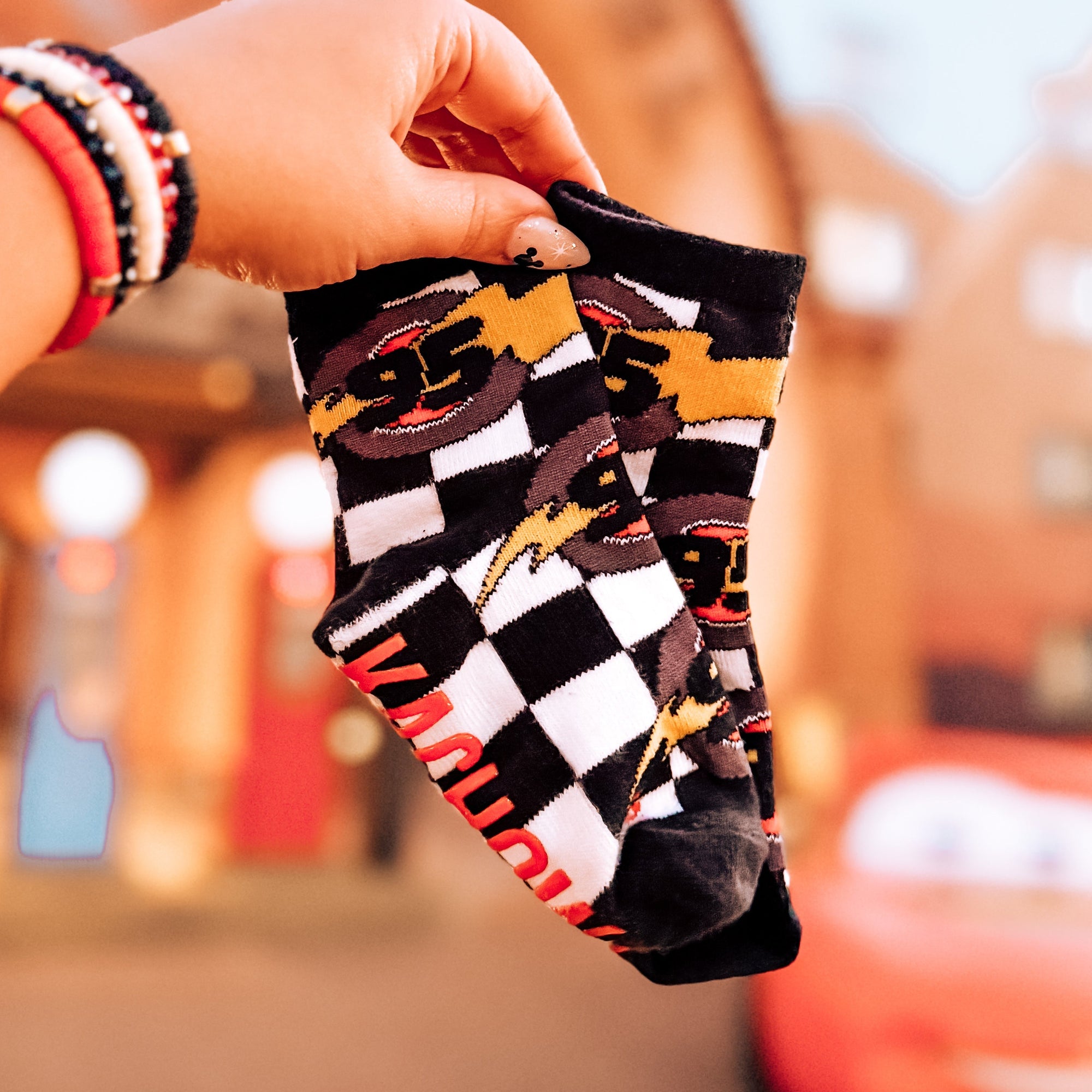 Person holding a checkered sock with a blurred amusement park background
